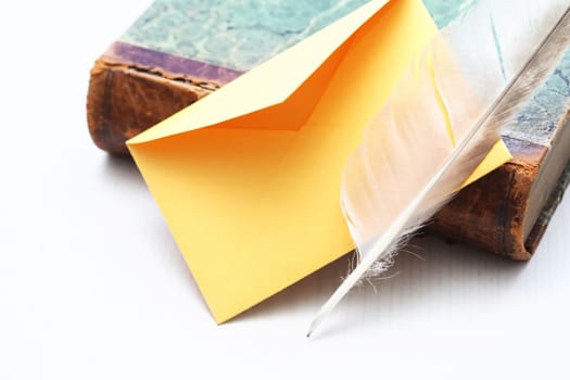 Still life with book and quill pen near empty envelope