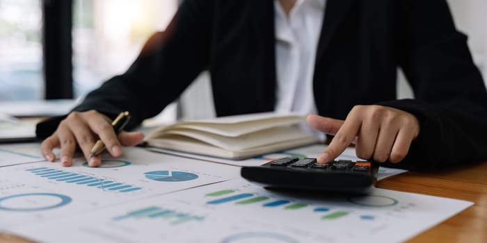 Close up hands of a business accountant woman using a calculator to analysis financial accounts check the company's expenses and budget.