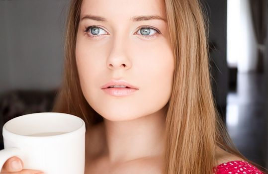 Beautiful woman having a cup of tea in the morning at home.