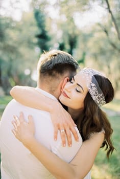 Bride hugs groom by the shoulders. Close-up. High quality photo