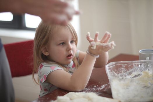 Happy loving family are preparing bakery together. Mother and child daughter girl are cooking cookies and having fun in the kitchen. Homemade food and little helper.