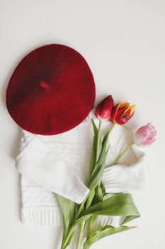 creative trendy flatlay with knitted sweater and fresh tulips, top view. Fashion, vintage mood and lifestyle concept. Cozy spring composition