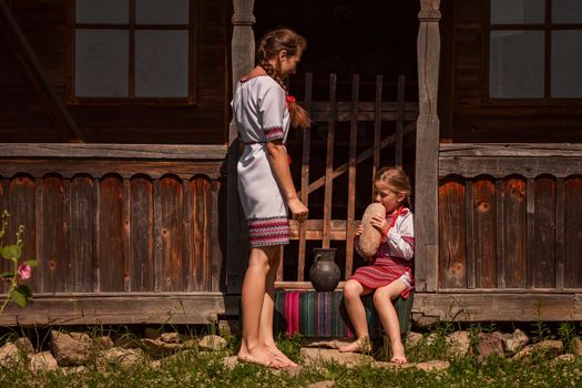 mother and daughter in Ukrainian folk dresses on the threshold of the house.