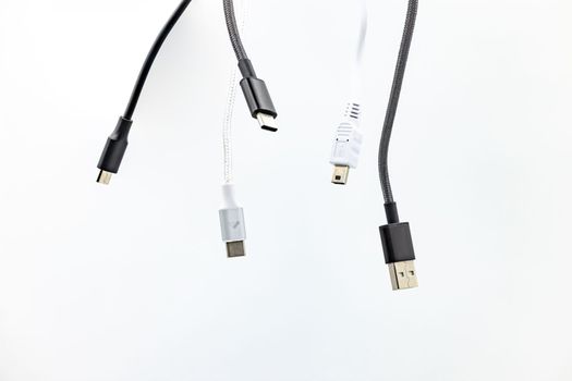 Jumble with many cables, USB plugs and standards isolated against a white background
