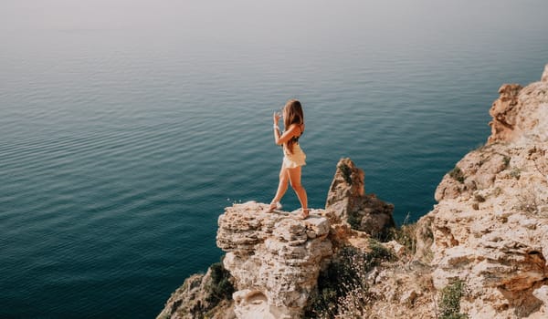 Woman travel sea. Happy tourist taking picture outdoors for memories. Woman traveler looks at the edge of the cliff on the sea bay of mountains, sharing travel adventure journey.