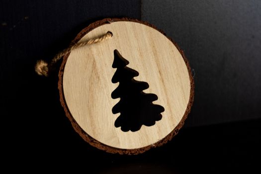 Wooden christmas ornament with a tree-shaped hole handmade. High quality photo with black background.