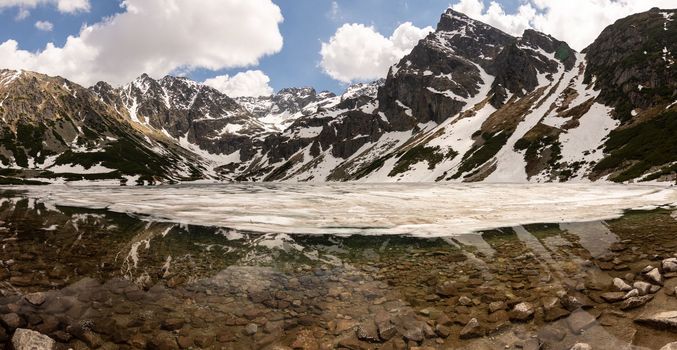 Mountain Lake of Czarny Staw Gasienicowy covered with snow and surrounding peaks of Tatra Mountains in Zakopane, Poland. High quality photo