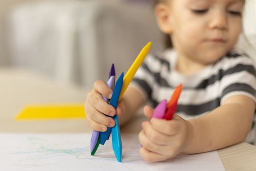 cute caucasian baby girl drawing greeting card for mothers day. Image with selective focus on hand