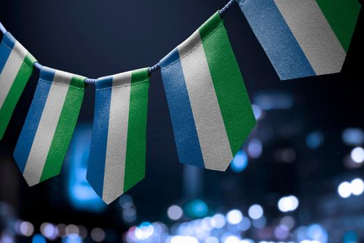 A garland of Sierra Leone national flags on an abstract blurred background.