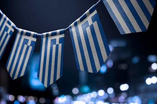 A garland of Greece national flags on an abstract blurred background.