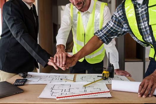 Architecture team stacking hands working together. Architectural plan, civil, engineer sketching a construction project concept