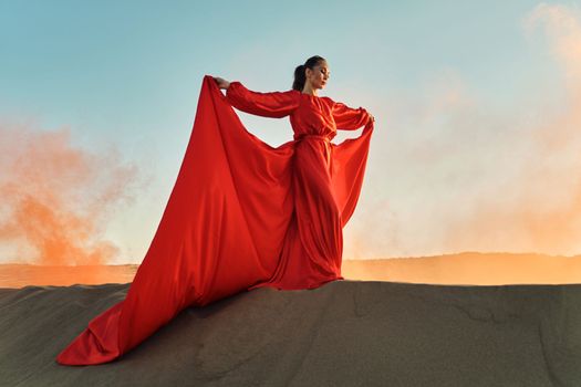 Woman in red dress dancing in the desert at blue sky