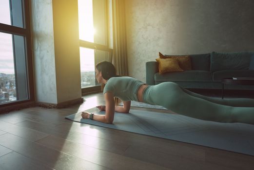 Young fit athlete woman doing plank exercise during home workout or home training. Crossfit or gymnastics concept. . High quality photo