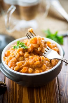 beans stewed with vegetables, mushrooms and spices, in a bowl, on a wooden table.