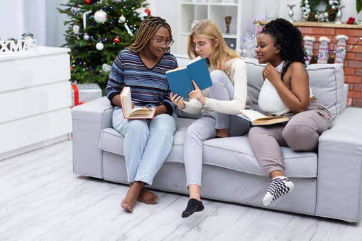 Astonishing information in a book read by female students. A dark-skinned girl wearing glasses. A living room decorated for Christmas.