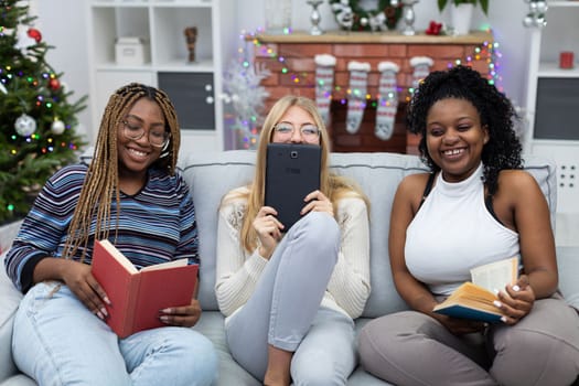 The girls laugh. Read a book. She reads the information on the blackboards. An African and a European woman wear glasses. Christmas decoration of the living room.