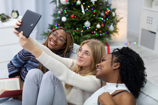 Joyful fun with a tablet while taking pictures of yourself. Selfie with friends. Christmas decoration of the living room.