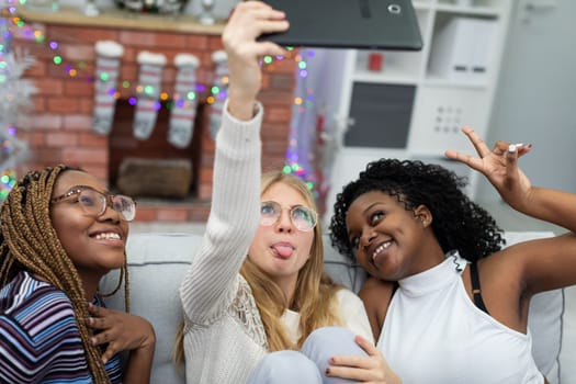 Friends take a selfie together by the decorated fireplace for Christmas. Friends from Africa and Europe.