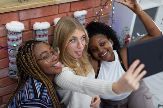 Crazy tablet photos of three friends right by the fireplace. Christmas decoration of the living room. Sudeten friendships.