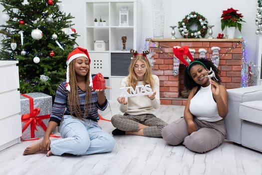 The girls enjoy the reunion. Christmas spent among friends from Africa and Europe. Female students hold Christmas accessories in their hands.