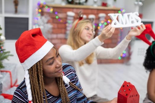 Happy African and European classmates experience Christmas together. Female students hold Christmas paraphernalia in their hands.