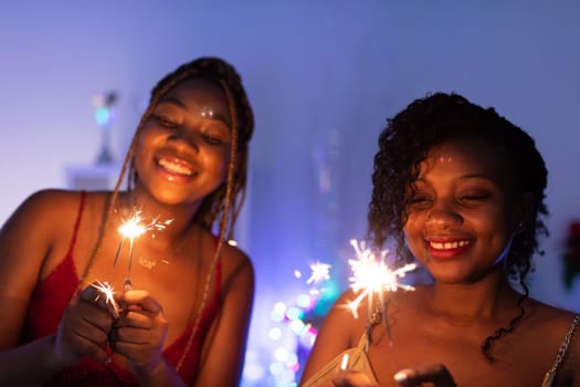 Burning cold fires. Two smiling African women play with burning cold fires. Christmas fun.