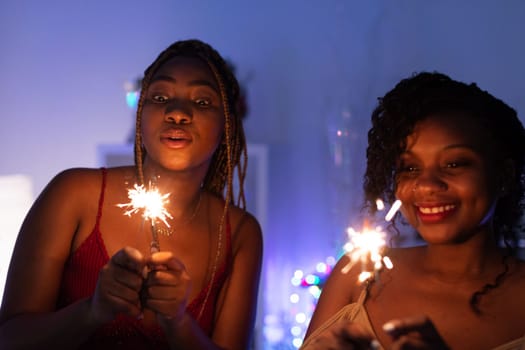 Burning cold fires. Two smiling African women play with burning cold fires. Christmas fun.