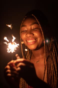 New Year's Eve fun with cold fires. An African woman and her wonderful smile. Happiness and joy is drawn on the young girl's face.