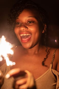 New Year's Eve fun with cold fires. An African woman and her wonderful smile. Happiness and joy is drawn on the young girl's face.