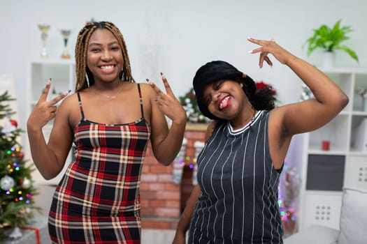 Hands in the air. Laughter and satisfied faces. African women rejoice. A room decorated for Christmas. Energetic scene during Christmas Eve.