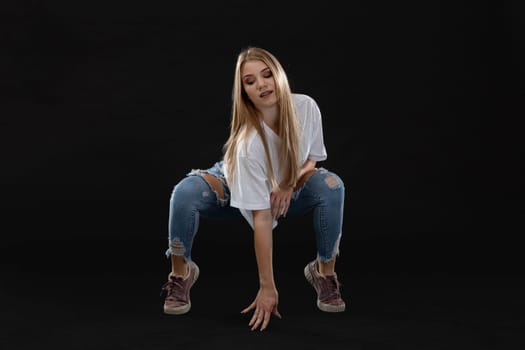 Dance figure. A teenage girl crouches down and stands on stilts. She is looking downward. Young professional dancer.