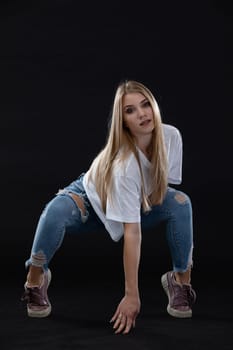 Dance figure. A young dancer crouches and stands on stilts. She looks directly into the camera. Young professional dancer.