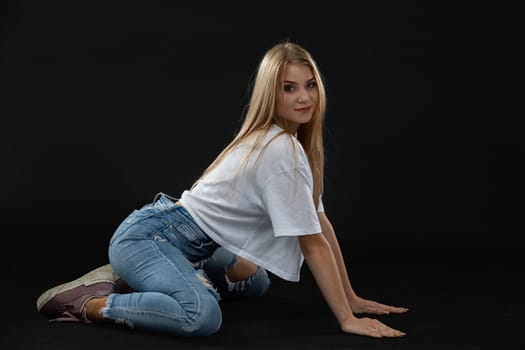Dance figure. A young dancer kneels in a seated position and looks straight at the camera. Young professional dancer.