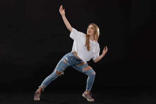 Dance figure. Young dancer in wide straddle places hands gently. Young professional dancer.