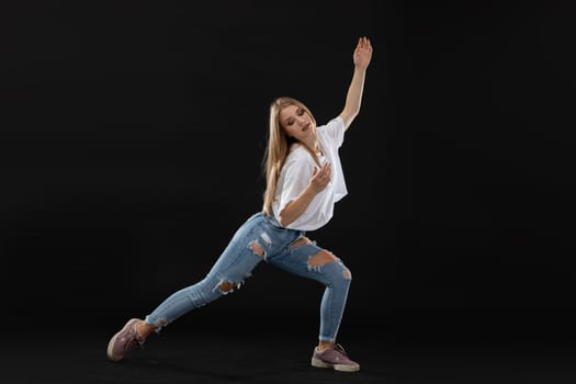 Dance pose. A teenage dancer stands wide apart and places her hands delicately. She looks down. A young professional dancer.