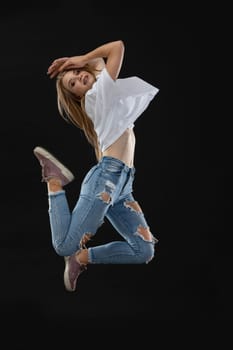 Dance pose in the air. A teenage dancer creeps upward, holding her hands on her head. She looks into the camera. Young professional dancer.