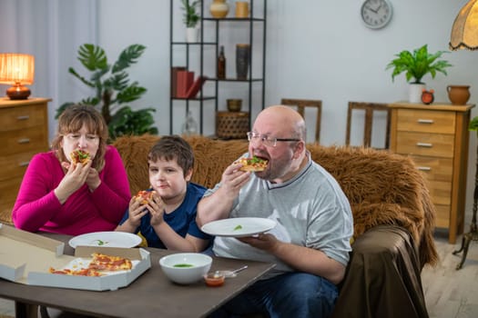 The whole family savors the taste of the pizza they are eating. Father, son and mother all eat pizza on thin crust.