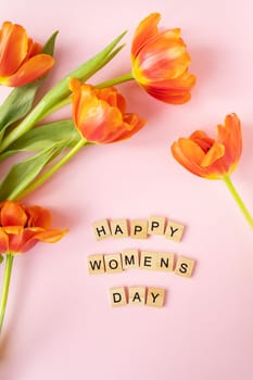 March 8, postcard. Happy Women's Day text sign on orange tulips background. Stylish flat lay with flowers and text, greeting card