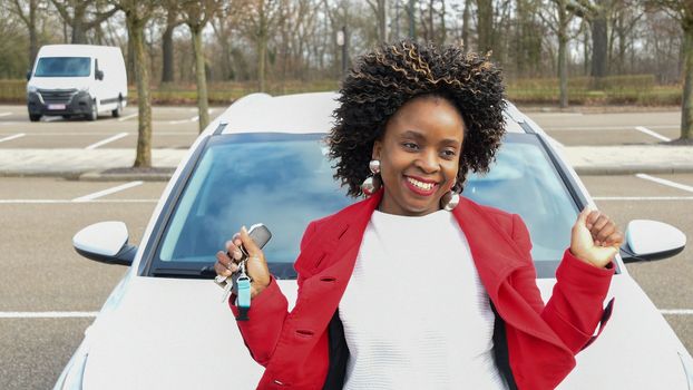 a cheerful african american woman stands next to the car and holds the keys to it in her hand, high quality photo, High quality photo