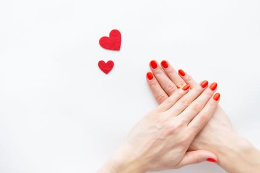 Nail care and manicure. Beautiful female hands with a red nail and a red heart. Place for an inscription. Valentine's Day