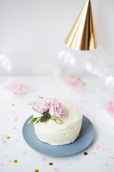 Very beautiful small white cake decorated with natural flowers eustoma on the background candy, balloons, cap. Holiday concept