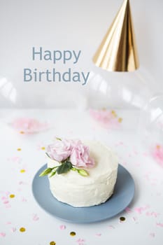 Very beautiful small white cake decorated with natural flowers eustoma on the background candy, balloons, cap. Happy birthday lettering