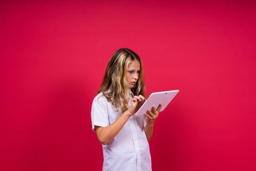 Online school app. Schoolgirl showing tablet computer Empty Screen On red Background. Studio Shot