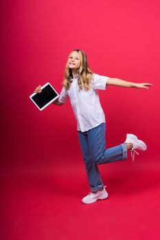 Online school app. Schoolgirl showing tablet computer Empty Screen On red Background. Studio Shot