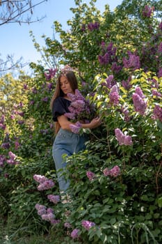 portrait of young woman with long hair outdoors in blooming lilac garden.