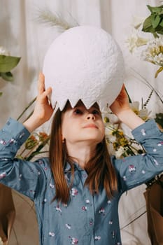 Girl in a beautiful Easter photo zone with flowers, eggs, chickens and Easter bunnies. Happy Easter holiday