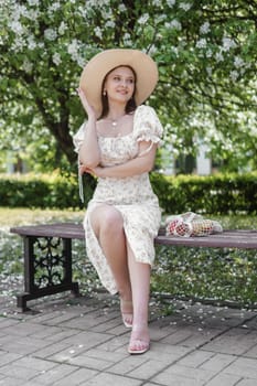 An attractive long-haired woman walks in the spring in the park of blooming apple trees. Spring portrait of a woman