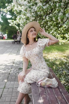 An attractive long-haired woman walks in the spring in the park of blooming apple trees. Spring portrait of a woman