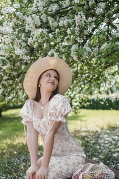 An attractive long-haired woman walks in the spring in the park of blooming apple trees. Spring portrait of a woman