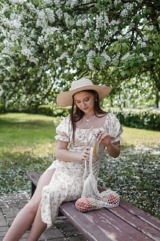 An attractive long-haired woman walks in the spring in the park of blooming apple trees. Spring portrait of a woman